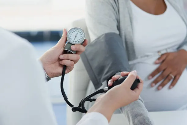High Blood Pressure During Pregnancy - drpallavichauhan Healthcare professional checks a pregnant woman's blood pressure with a sphygmomanometer.